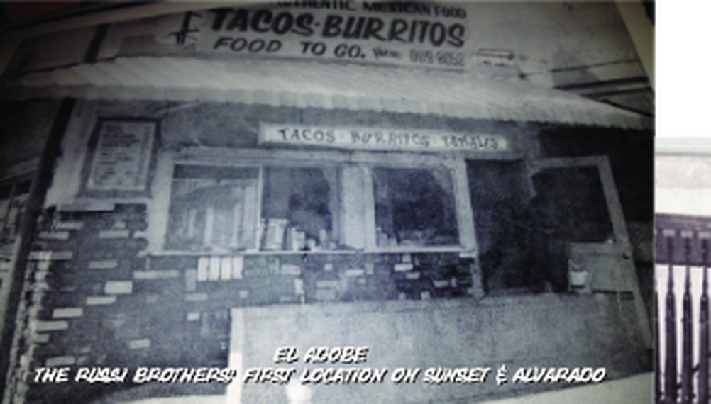 The Russi brothers' first location, El Adobe, on Sunset and Alvarado in Los Angeles. A small walk-up stand with a hand-painted sign reading Tacos, Burritos, Food To Go.